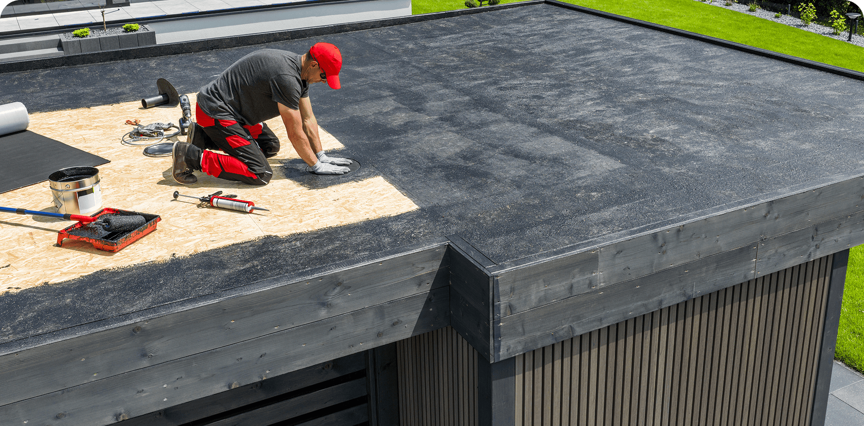 Worker installing flat roof waterproofing material.