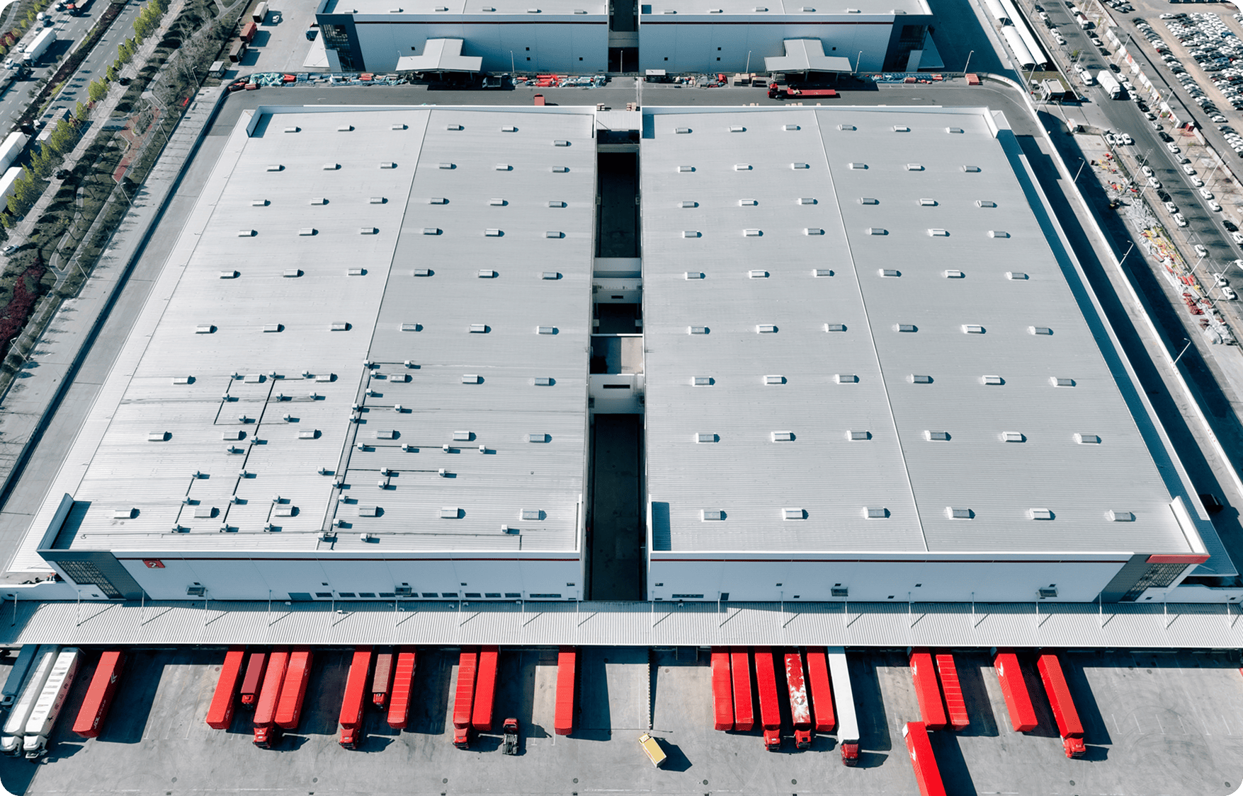Large warehouse with parked red trucks.